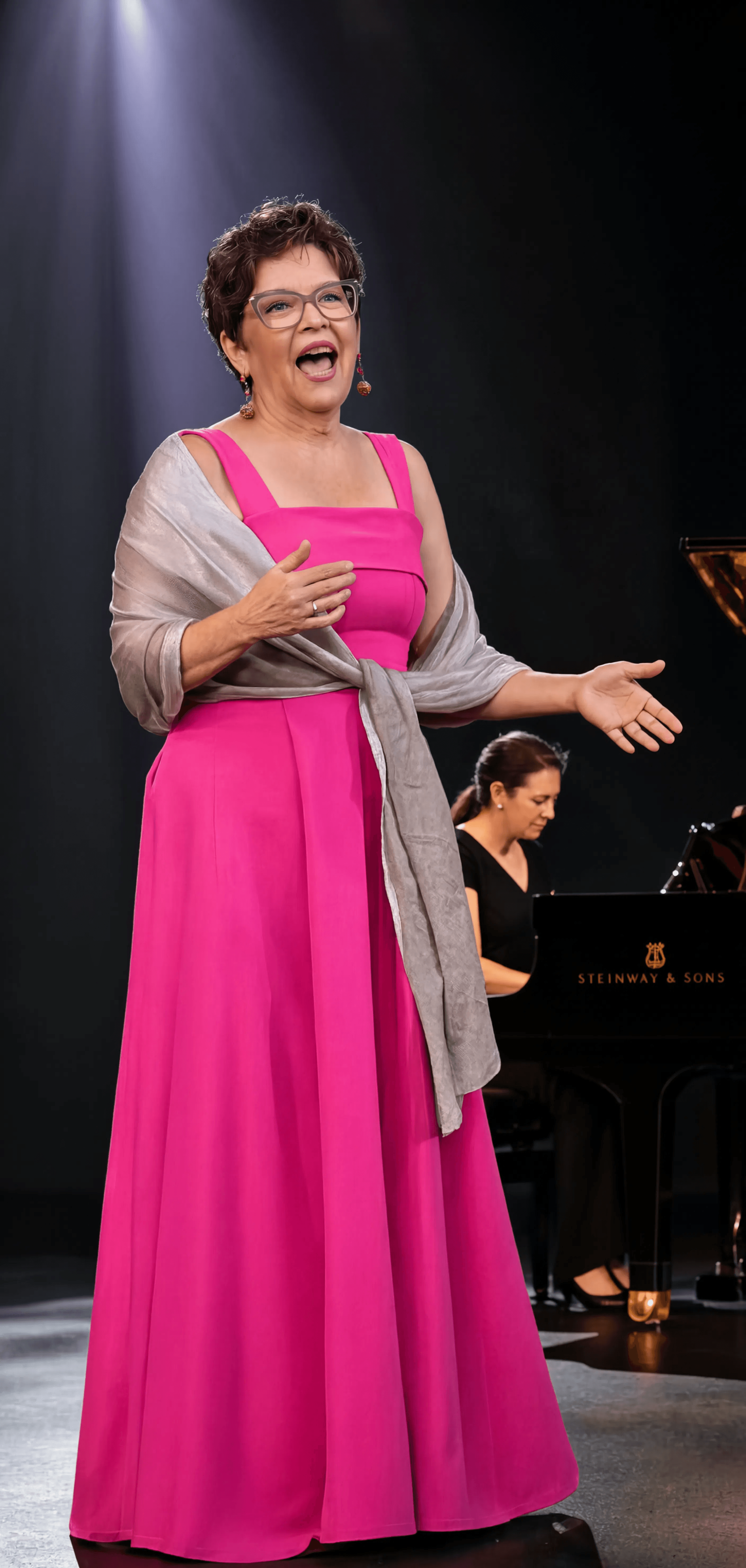 Mary Laymon performing on stage with piano accompaniment - Mary Laymon Voice Studio
